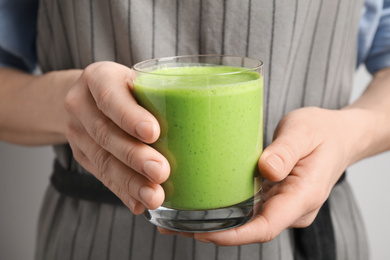 Woman holding tasty fresh kale smoothie, closeup