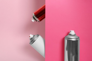 Photo of Different cans of spray paints on color background