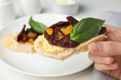 Photo of Woman eating delicious tomato bruschetta at table, closeup