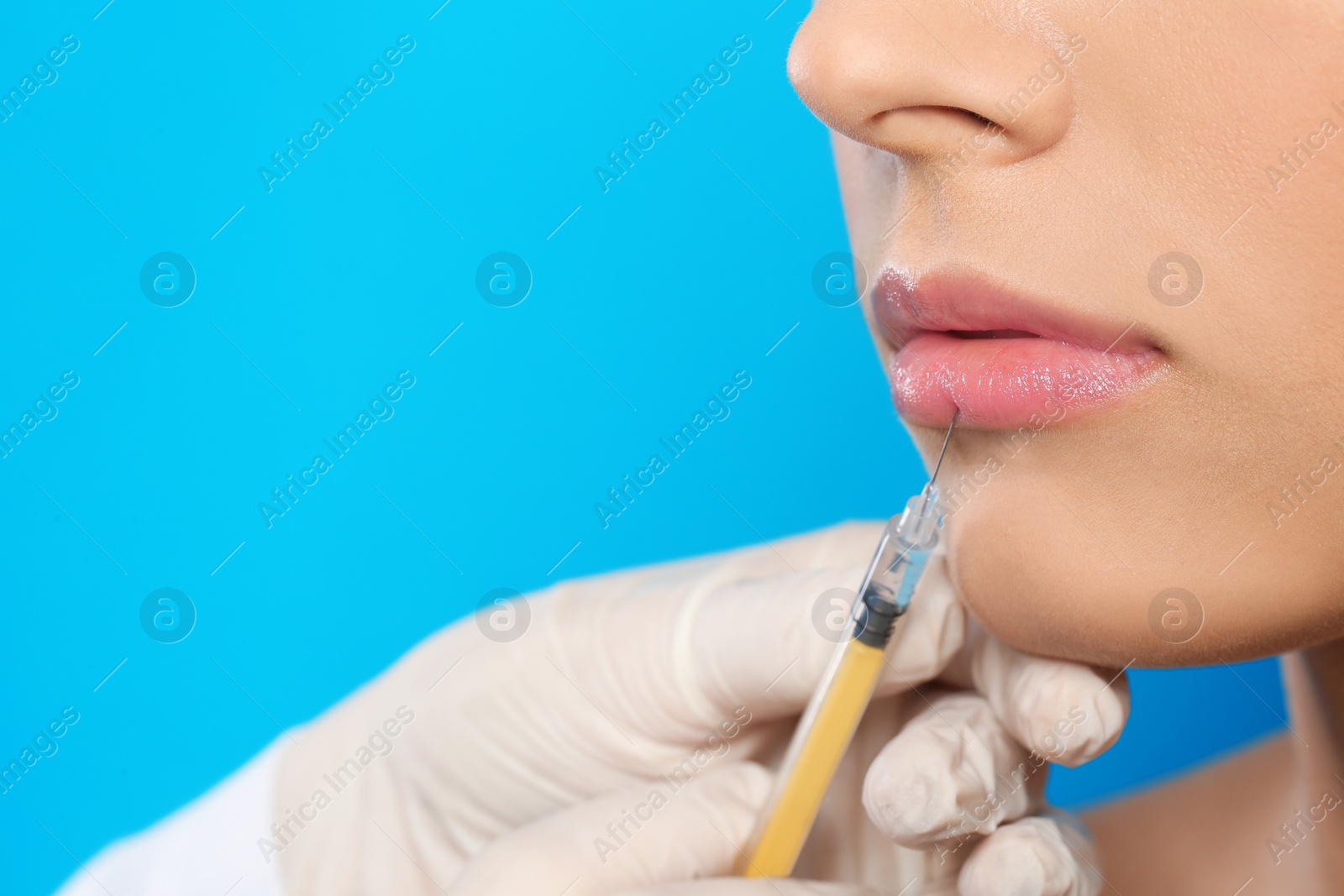 Photo of Young woman getting lips injection on color background, space for text. Cosmetic surgery