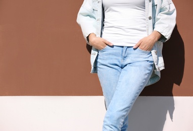 Photo of Young hipster woman in stylish jeans and jacket posing near color wall