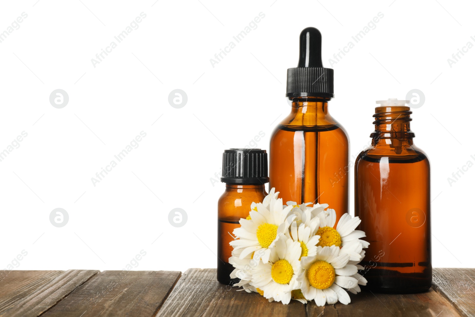 Photo of Chamomile flowers and cosmetic bottles of essential oil on wooden table against white background. Space for text