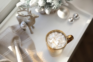 Photo of Golden cup of cocoa and Christmas decor on window sill indoors, above view