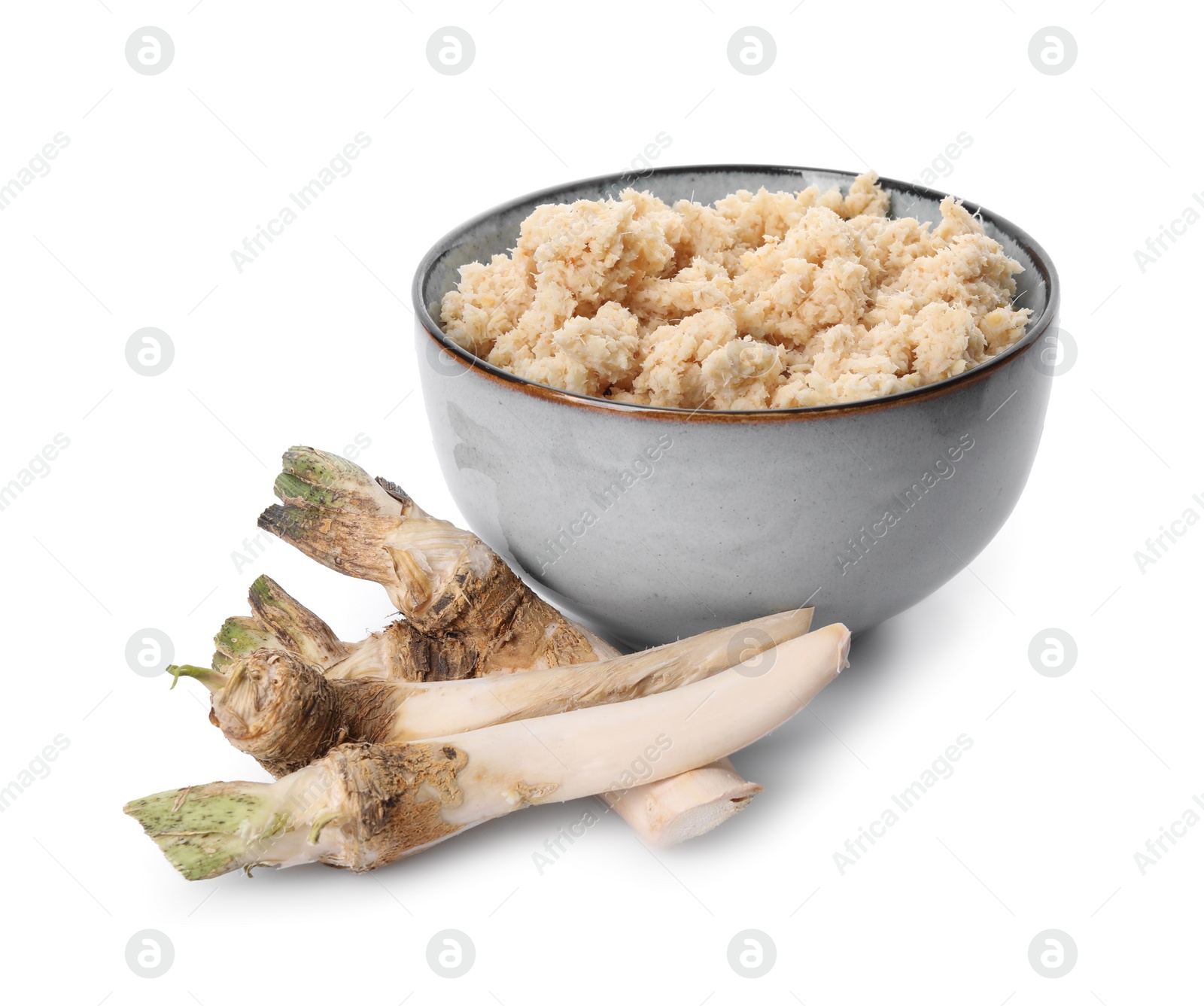 Photo of Bowl of tasty prepared horseradish and roots isolated on white