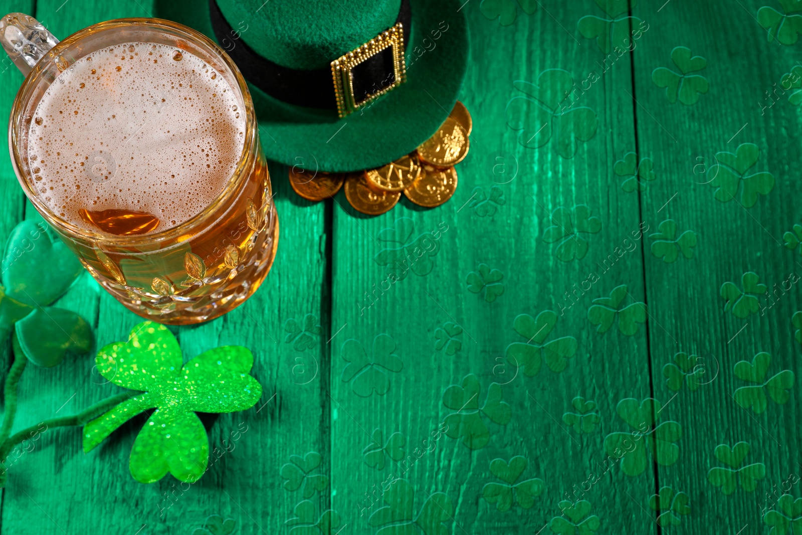 Image of St. Patrick's day. Beer, leprechaun hat, gold and decorative clover leaves on green wooden table. Space for text