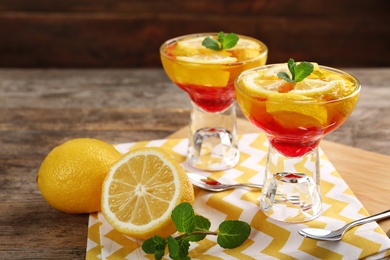 Dessert bowls of lemon jelly served on wooden table. Space for text