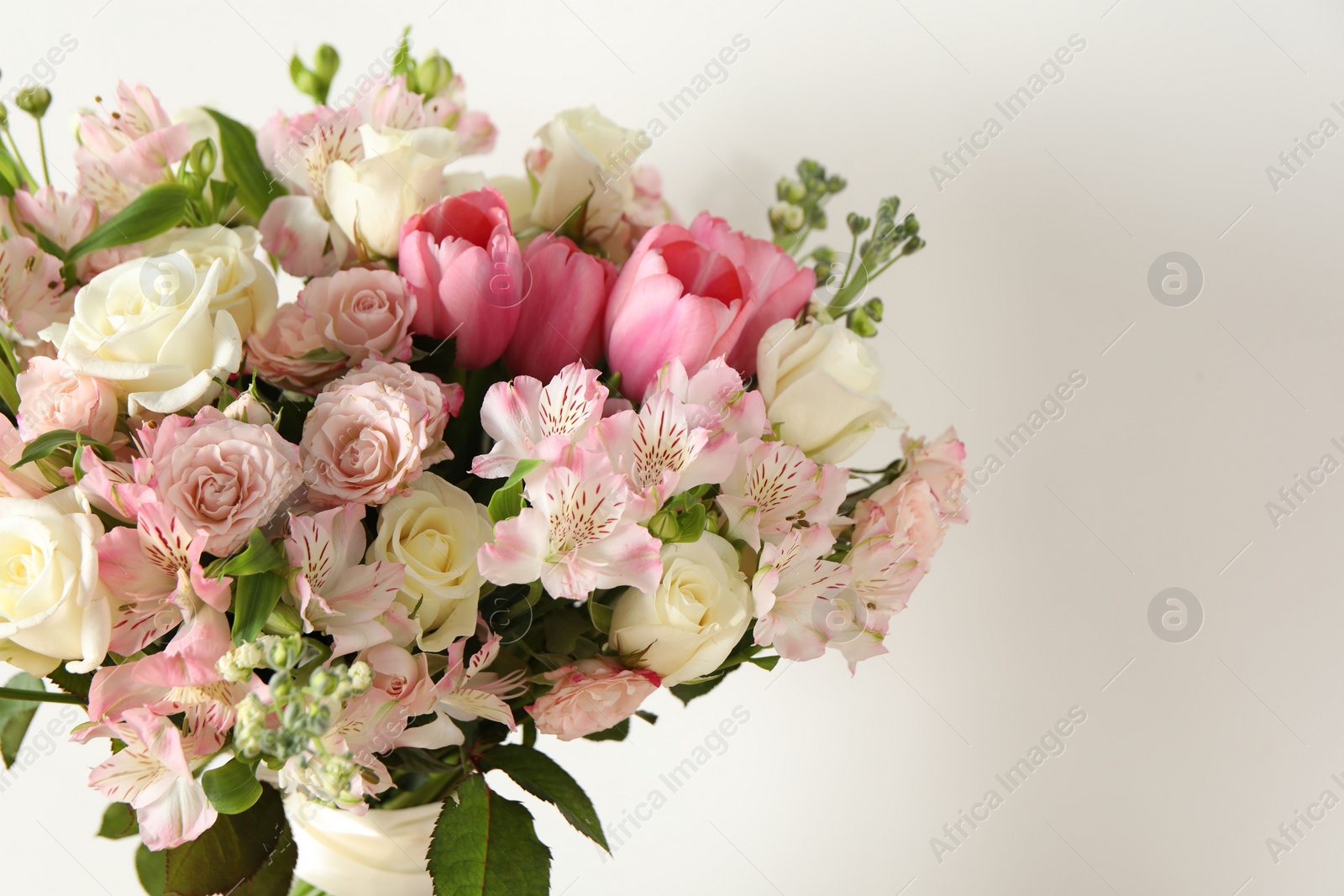 Photo of Beautiful bouquet of fresh flowers near white wall, space for text