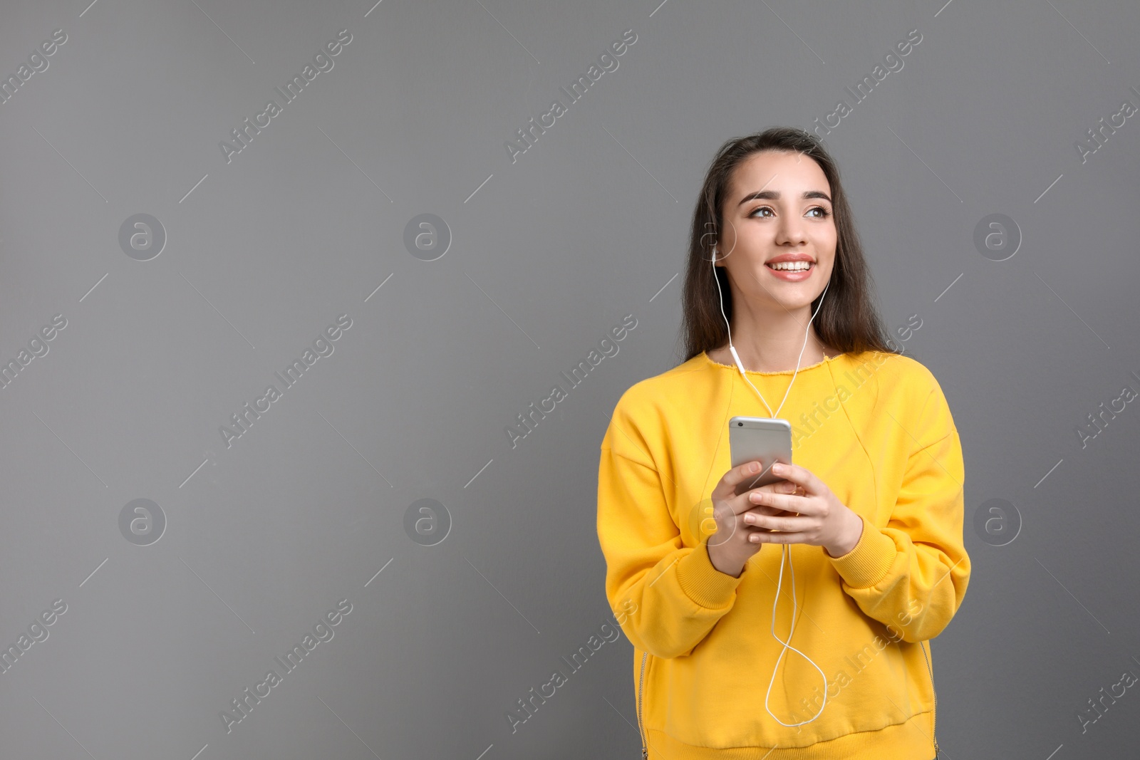 Photo of Young woman using phone for listening to music against color background