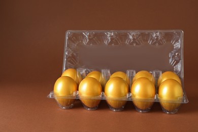 Photo of Shiny golden eggs in plastic box on brown background