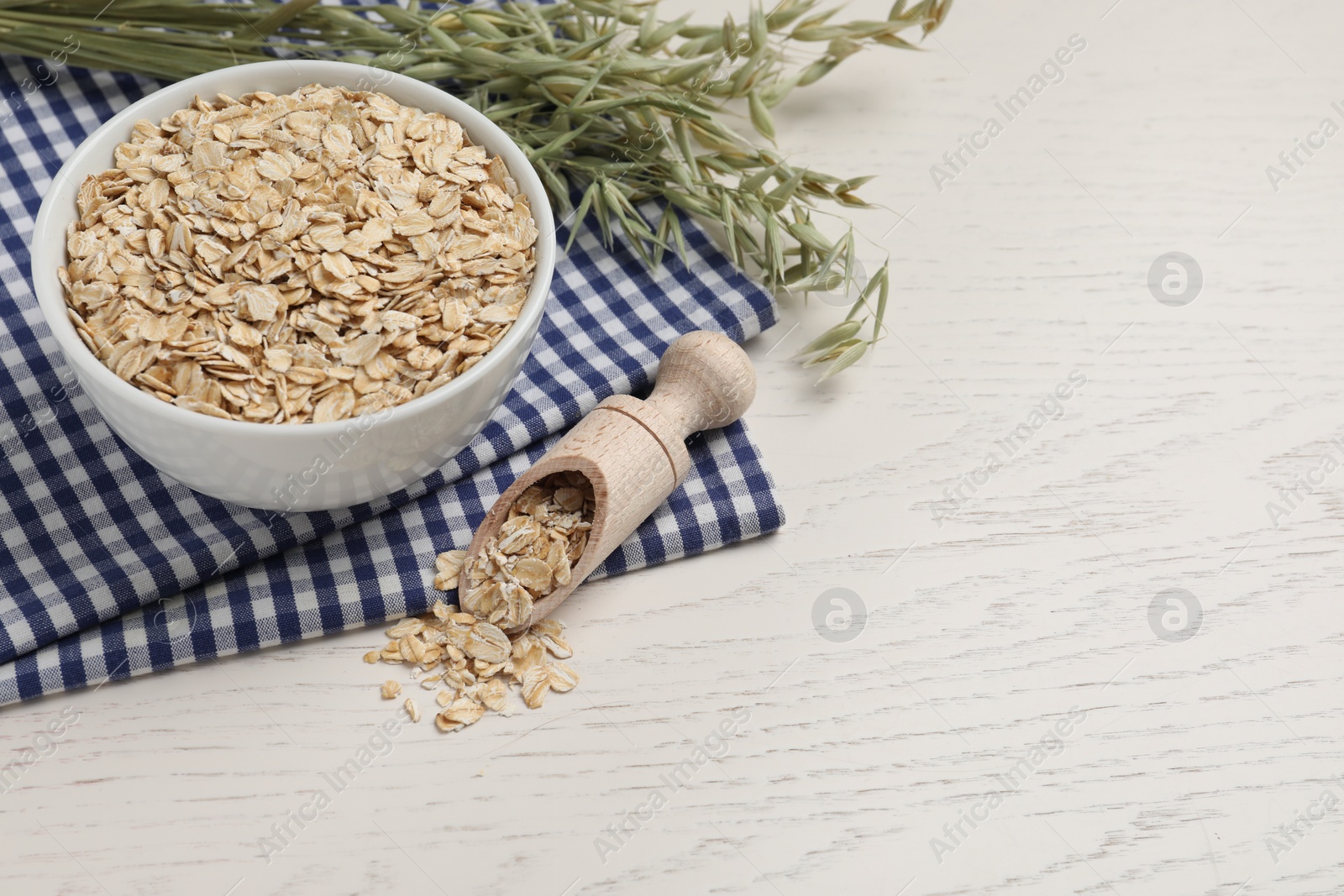 Photo of Oatmeal and branches with florets on white wooden table. Space for text