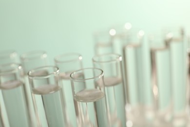 Photo of Many glass test tubes on light background, closeup