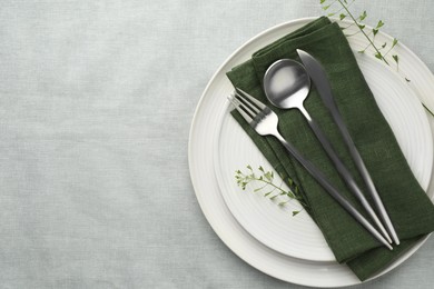 Photo of Stylish setting with cutlery, leaves and plates on grey table, top view. Space for text