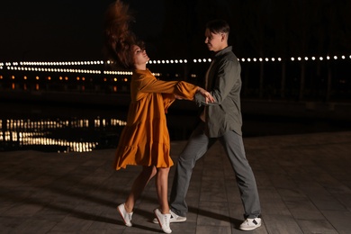 Photo of Beautiful young couple practicing dance moves in evening outdoors