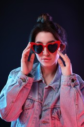 Photo of Portrait of young woman in sunglasses on color background