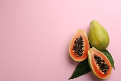 Fresh ripe papaya fruits with green leaves on pink background, flat lay. Space for text