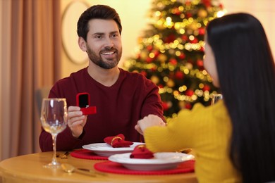 Photo of Man with engagement ring making proposal to his girlfriend at home on Christmas, selective focus