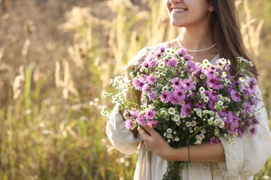 Woman holding bouquet of beautiful wild flowers outdoors, closeup. Space for text