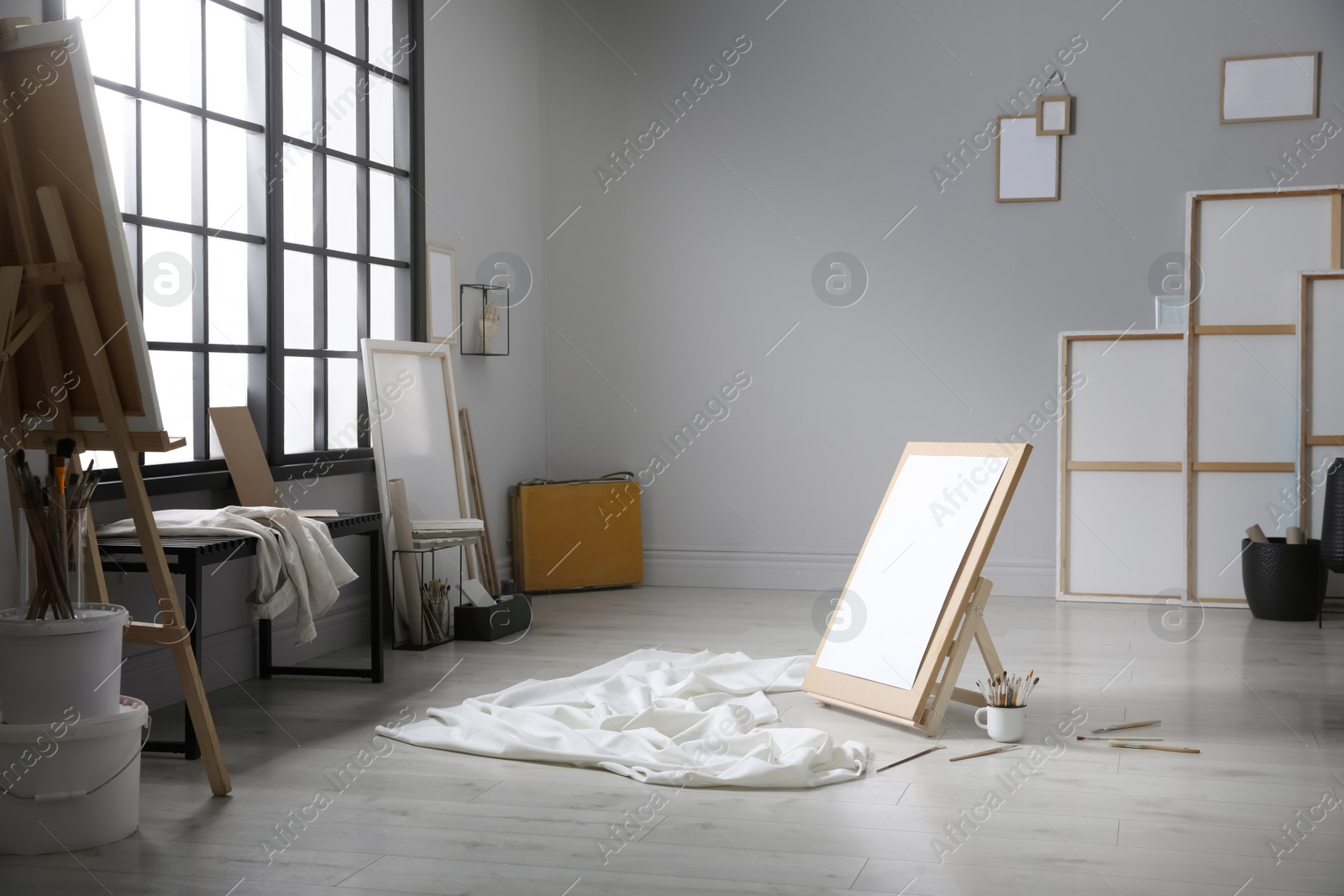 Photo of Stylish artist's studio interior with canvas, white fabric and brushes