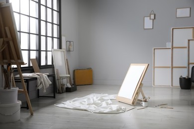 Stylish artist's studio interior with canvas, white fabric and brushes