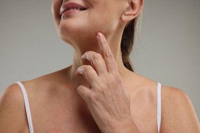 Mature woman with healthy skin on grey background, closeup