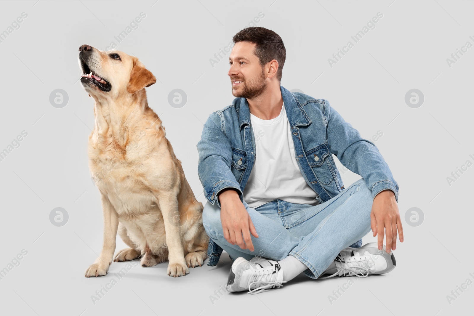 Photo of Man with adorable Labrador Retriever dog on light gray background. Lovely pet