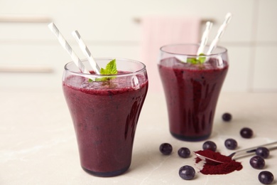 Photo of Glasses with delicious acai smoothie on table in kitchen