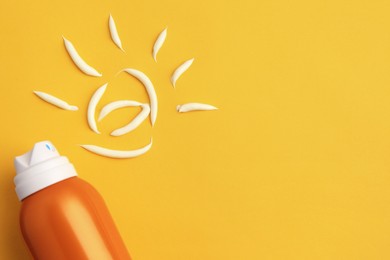 Photo of Drawing of sun and bottle with sunscreen on orange background, top view and space for text. Skin protection