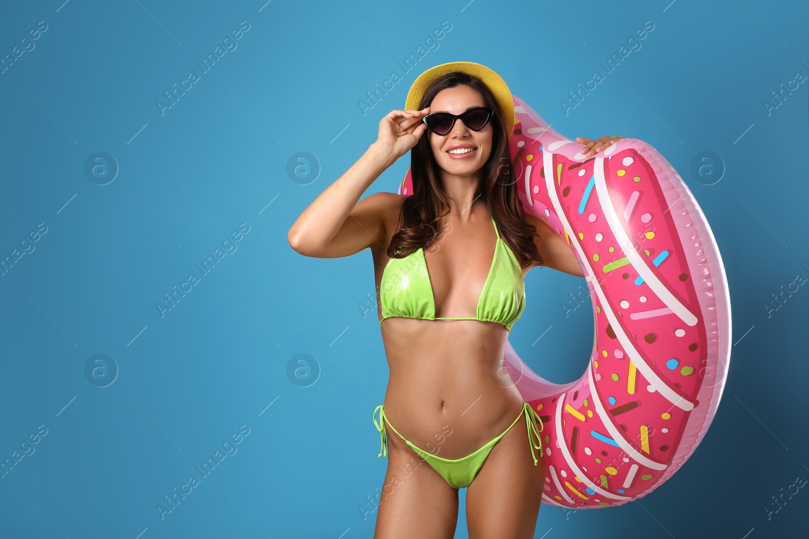 Photo of Beautiful woman in stylish bikini with inflatable ring on blue background. Space for text