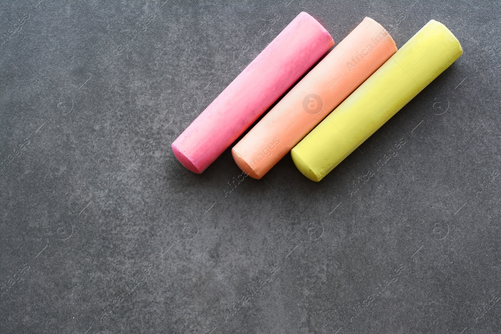 Photo of Colorful chalk sticks on black surface, flat lay. Space for text