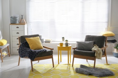 Photo of Armchairs with pillows and plaid in living room. Interior design