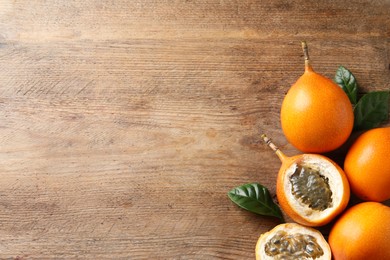 Photo of Delicious ripe granadillas on wooden table, flat lay. Space for text