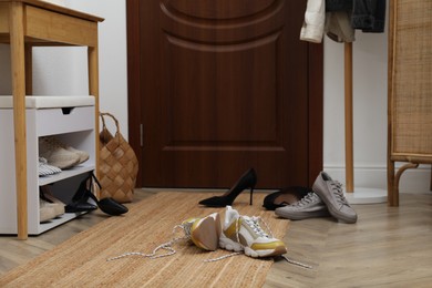 Photo of Different stylish shoes scattered on floor in hall