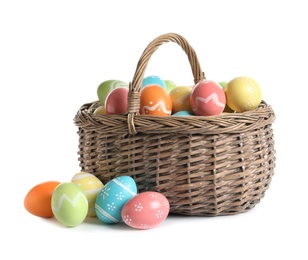 Wicker basket with painted Easter eggs on white background