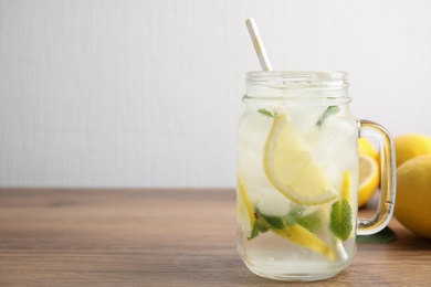 Mason jar of cold lemonade on wooden table. Space for text