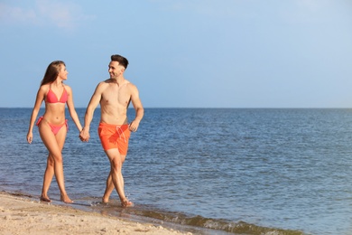 Young woman in bikini spending time with her boyfriend on beach. Lovely couple