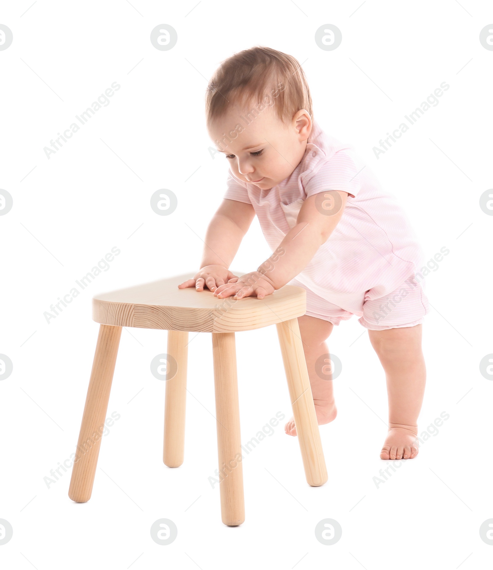 Photo of Cute baby holding on to wooden stool on white background. Learning to walk