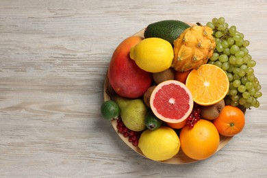 Photo of Different ripe fruits and berries on light wooden table, top view. Space for text