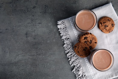 Flat lay composition with glasses of tasty chocolate milk and space for text on gray background. Dairy drink