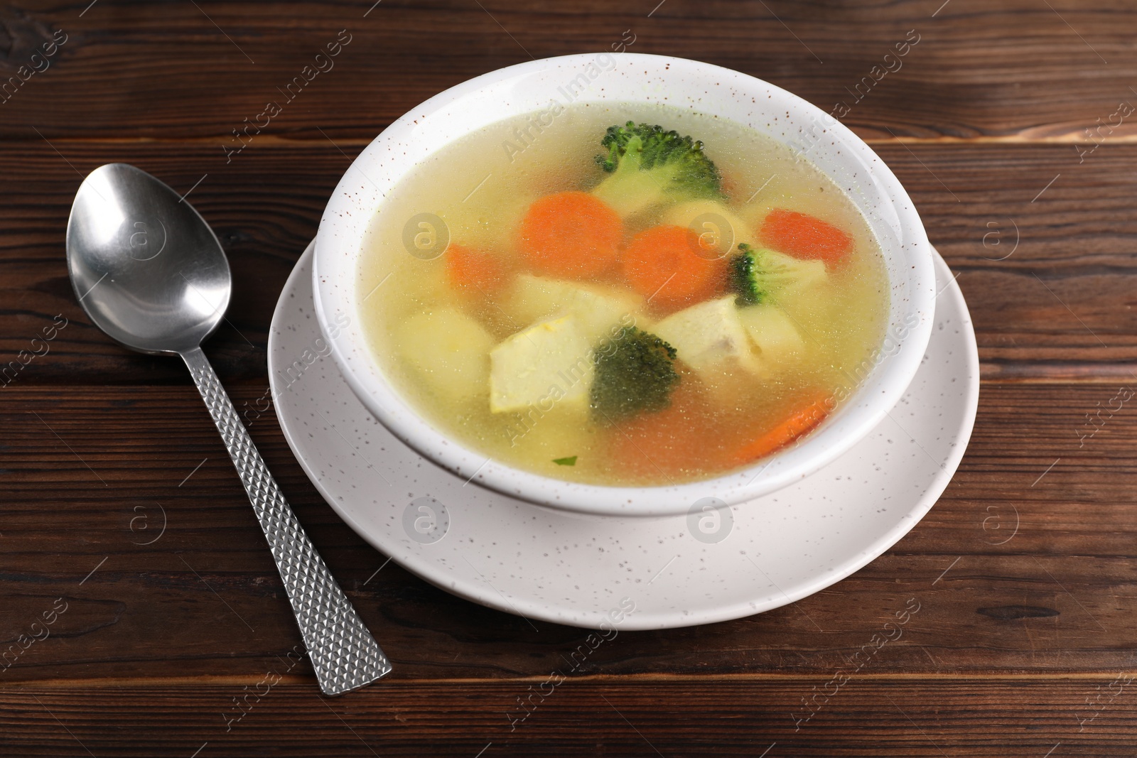 Photo of Tasty chicken soup with vegetables in bowl served on wooden table, closeup