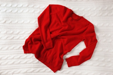 Photo of Red cashmere sweater on knitted plaid, top view