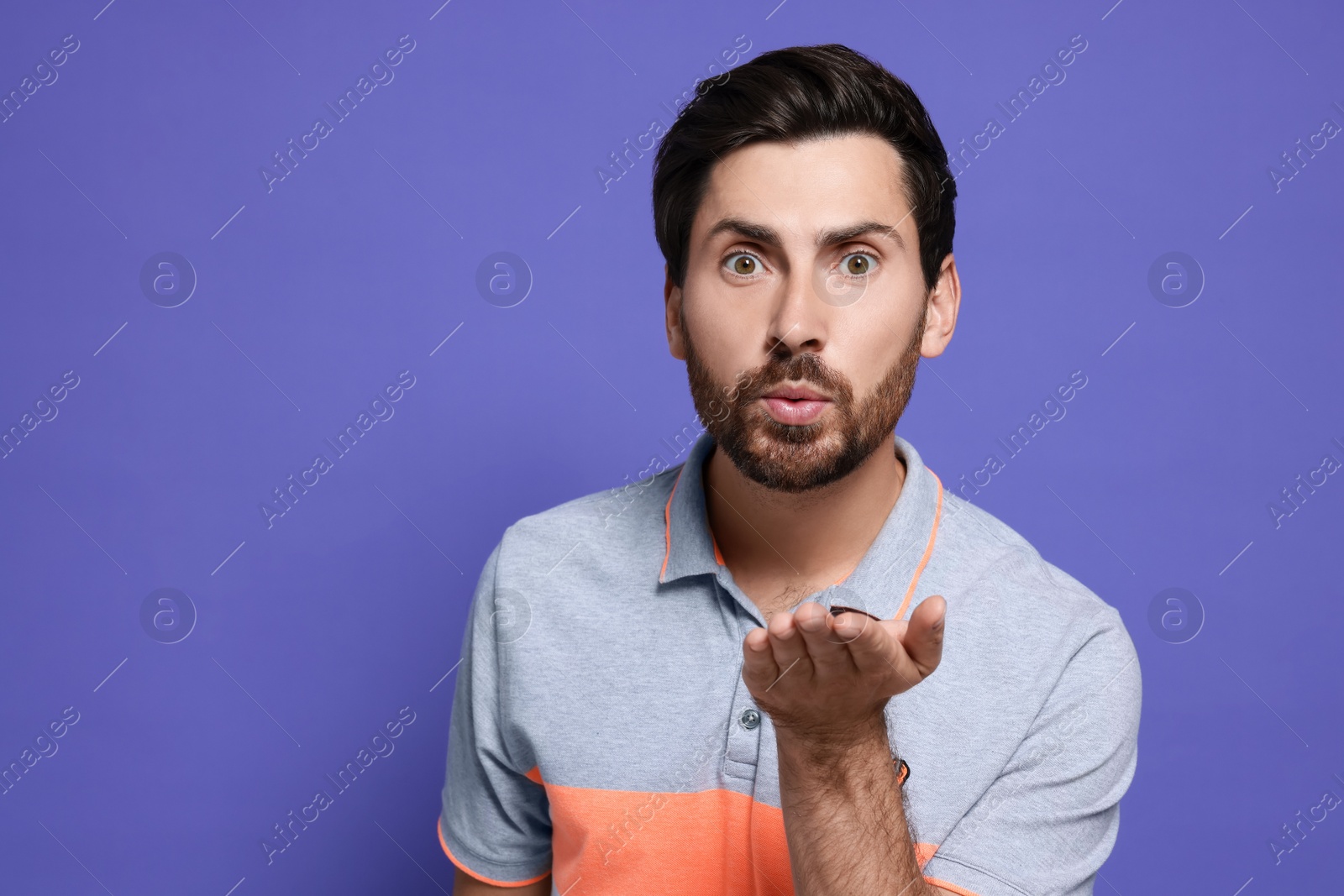 Photo of Handsome man blowing kiss on violet background. Space for text