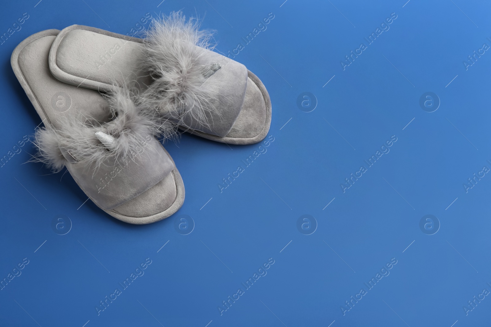 Photo of Pair of stylish soft slippers on blue background, flat lay. Space for text