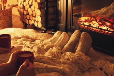 Photo of Couple in knitted socks near fireplace at home, closeup