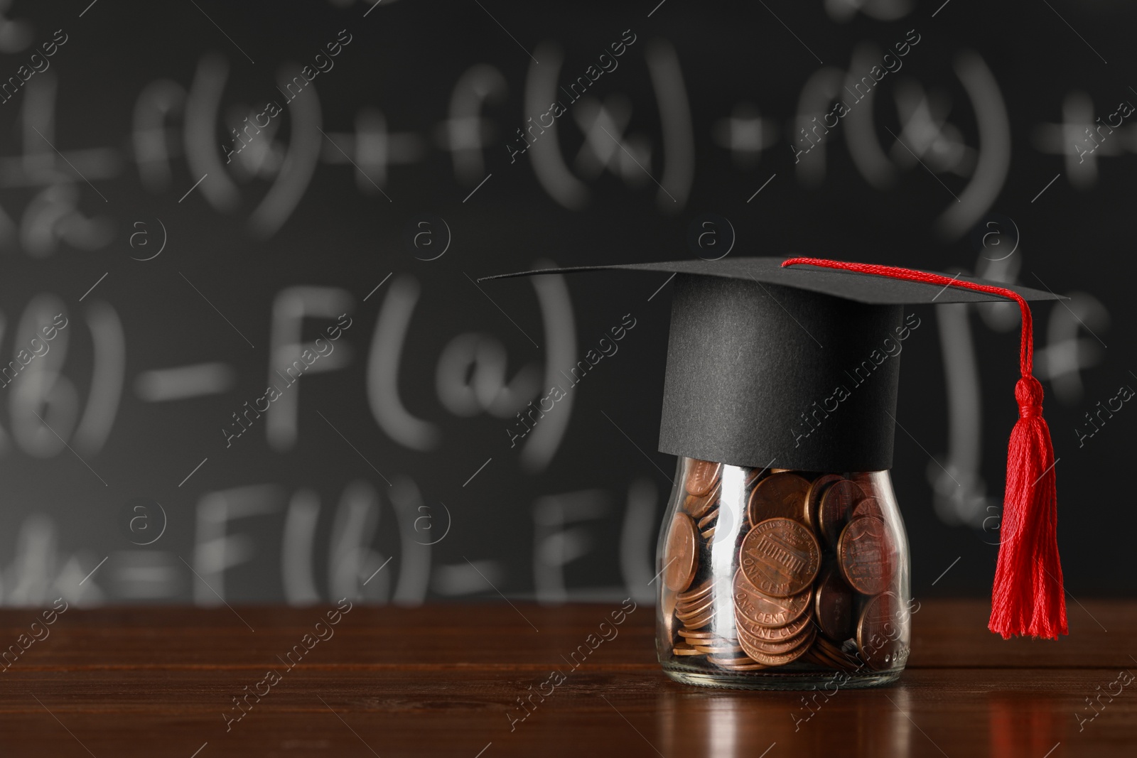 Photo of Scholarship concept. Graduation cap and jar with coins on wooden table, space for text