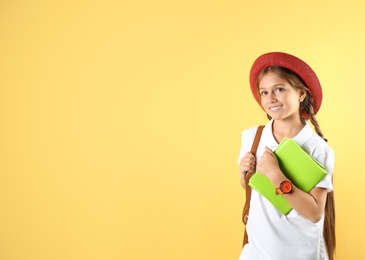 Pretty preteen girl with notebooks against color background. Space for text