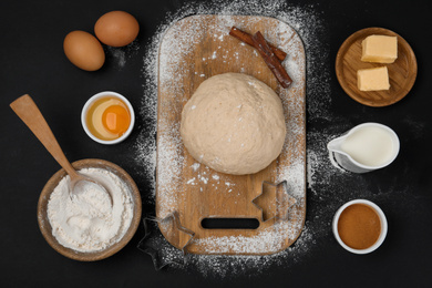 Flat lay composition with dough and other ingredients on black table. Baking pie