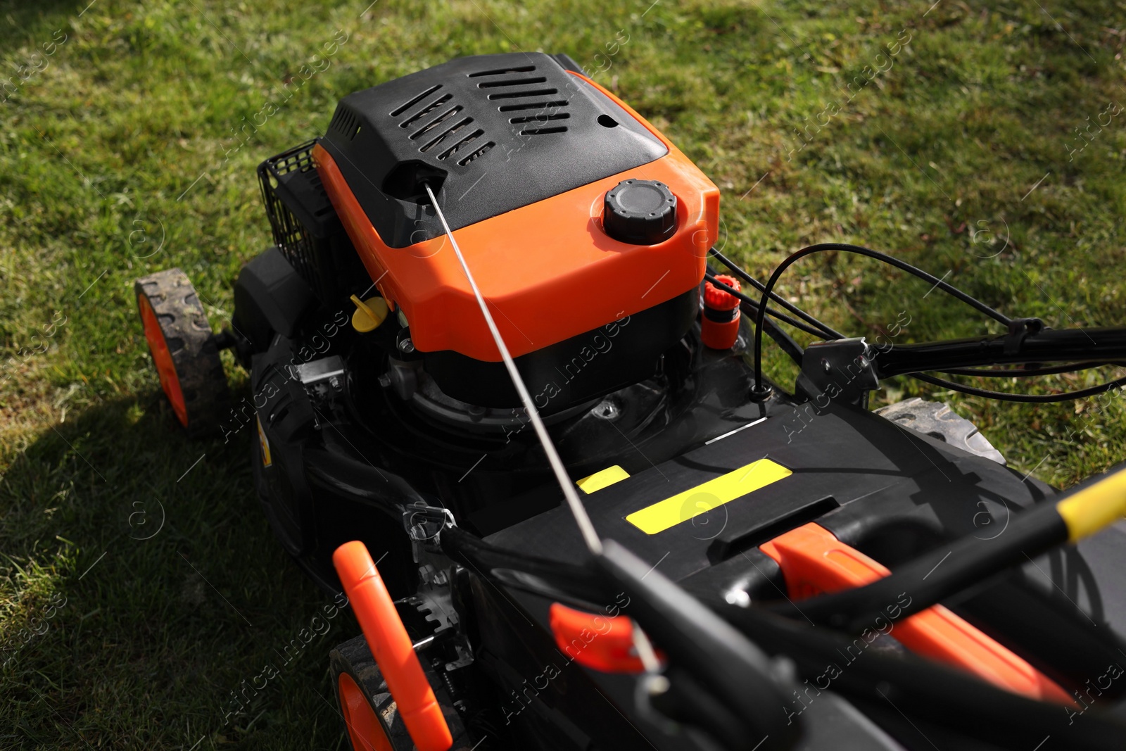 Photo of Modern lawn mower on green grass outdoors