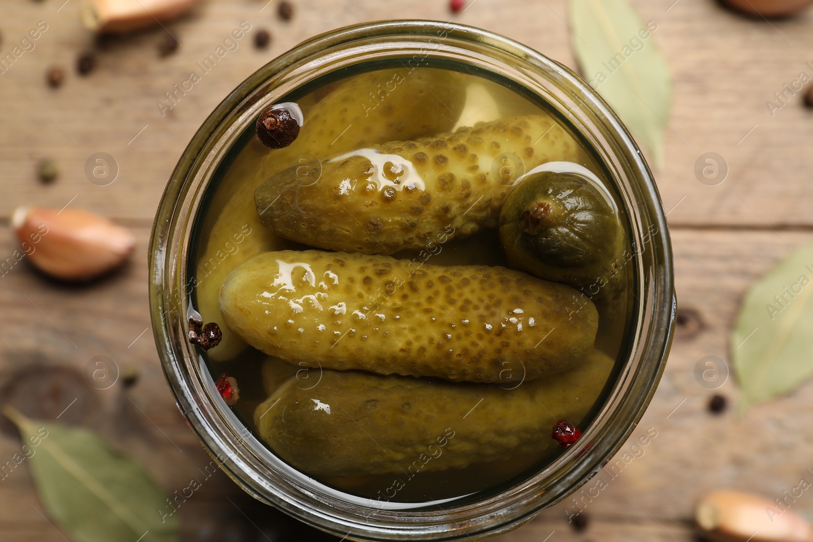 Photo of Tasty pickled cucumbers in glass jar on table, top view