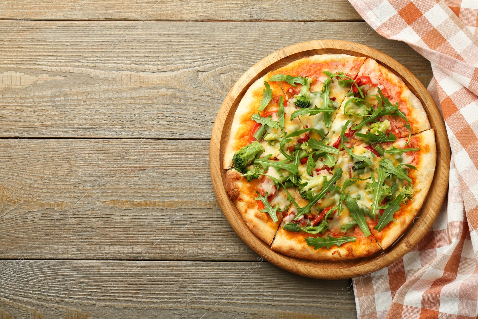 Photo of Board with delicious vegetarian pizza on wooden table, top view. Space for text