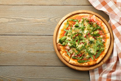 Board with delicious vegetarian pizza on wooden table, top view. Space for text